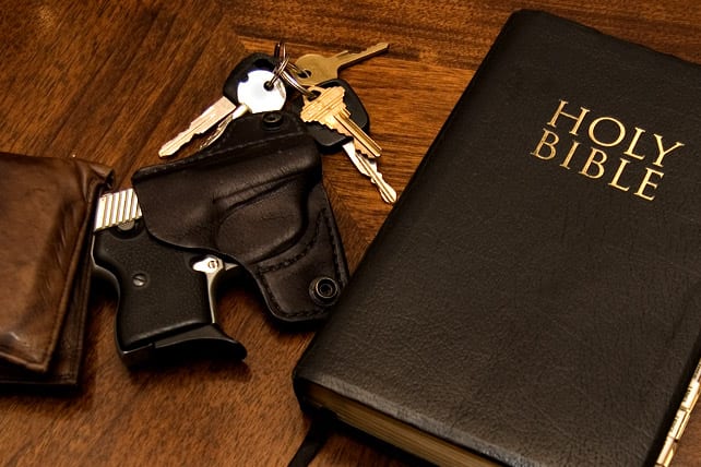 A handgun and keys are placed next to a Bible.
